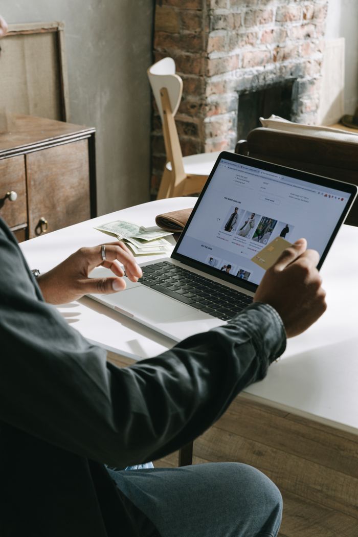 Un adulte utilise une credit card pour faire des achats en ligne sur un ordinateur portable à l’intérieur.
